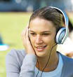 42-16225521 - Front view of three young people sitting on grass studying and wearing headphones